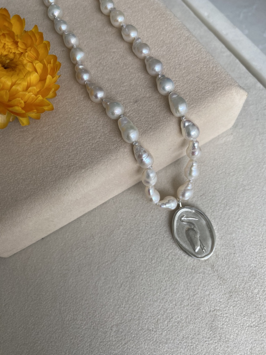 Areia awakens Heron pendant on Baroque pearl necklace